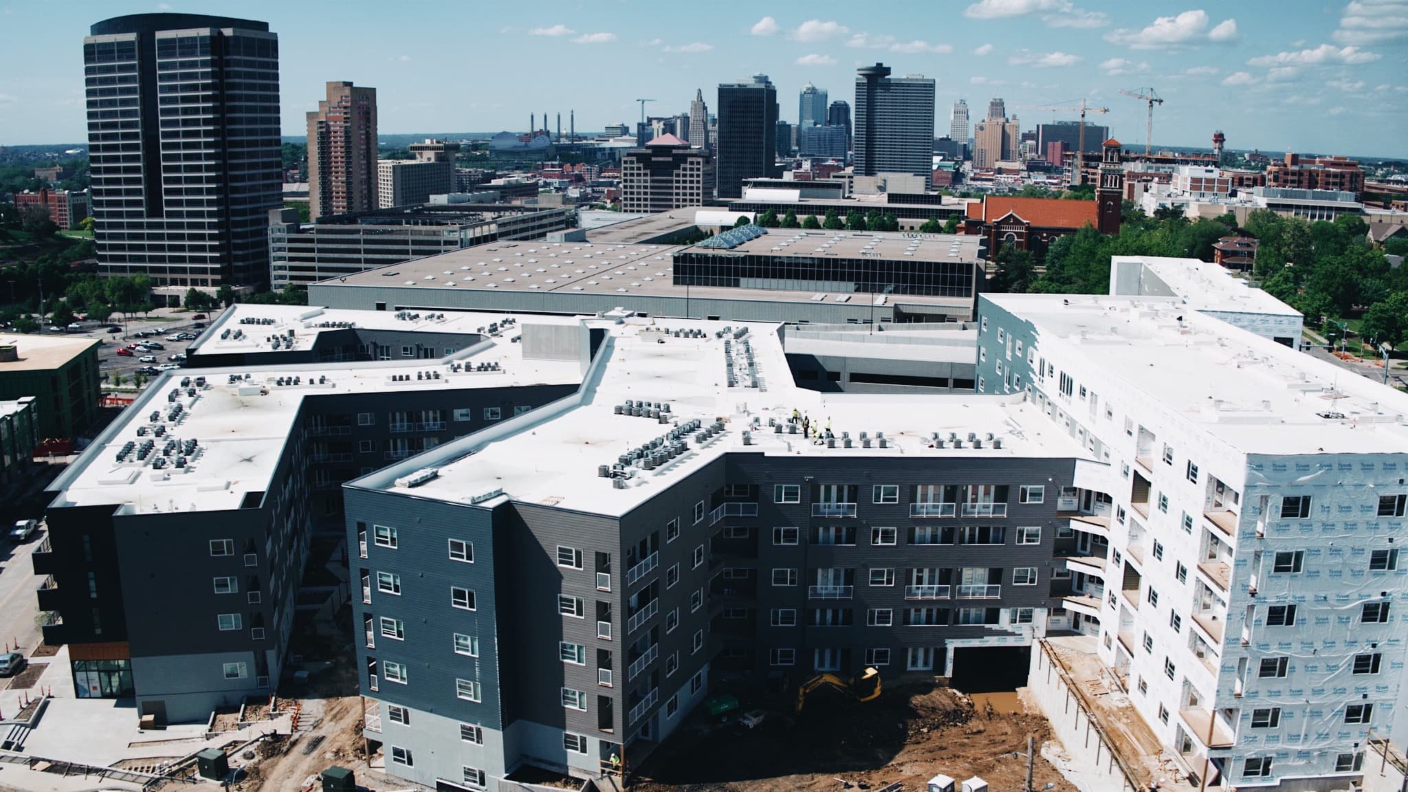 Aerial view of a multifamily construction project with the Kansas City skyline behind it
