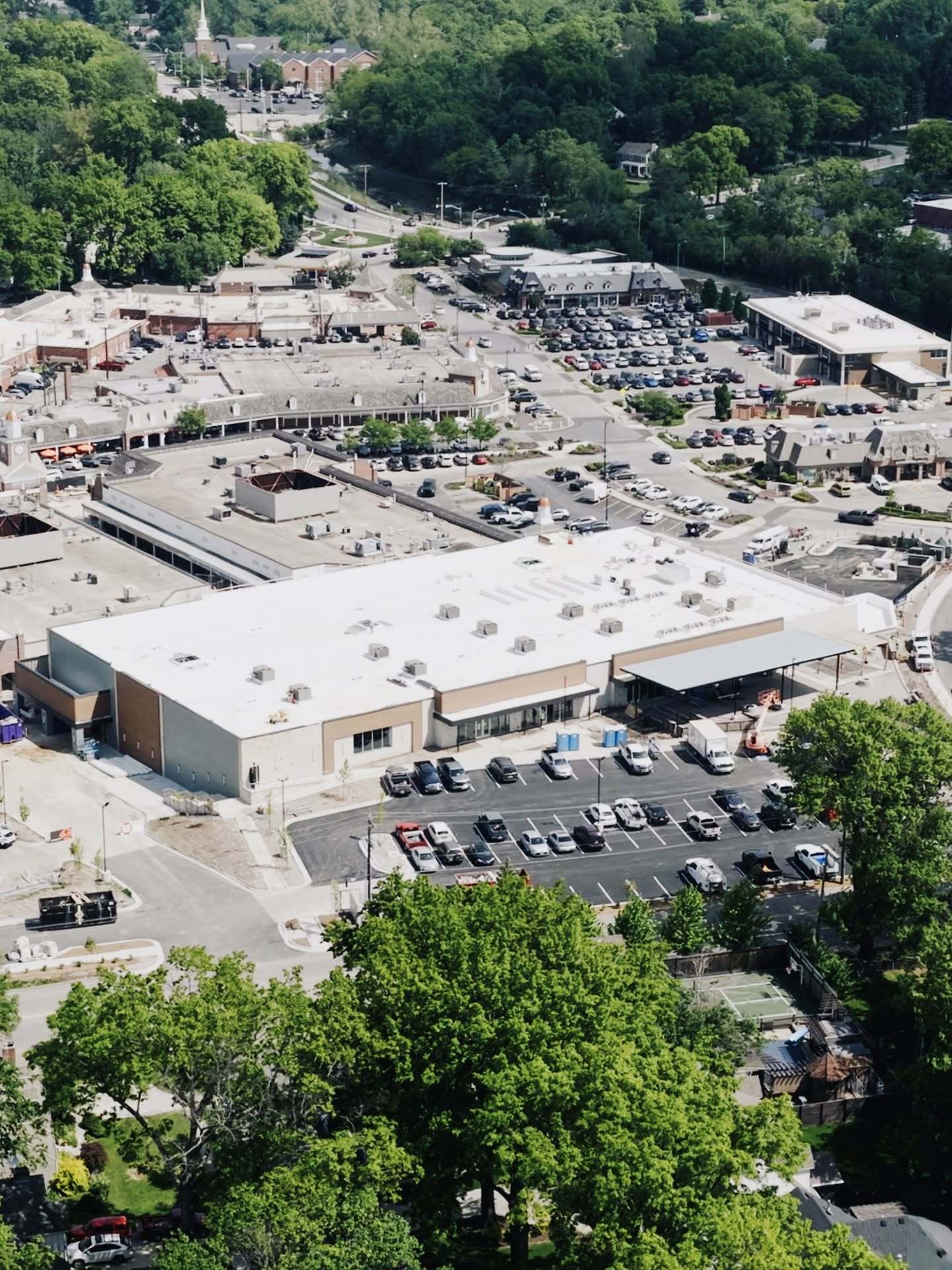 Aerial view of a suburban commercial center with white flat roofs under construction by JR&CO
